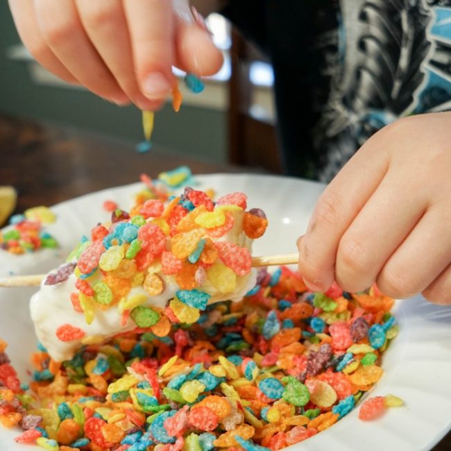 rolling banana skewers in fruit pebbles